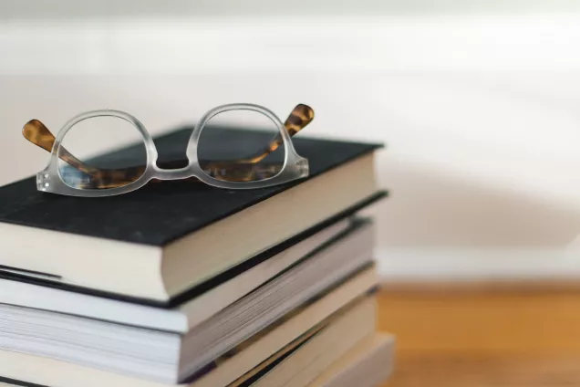 Stack of books with a pair of glasses on top. Photo.