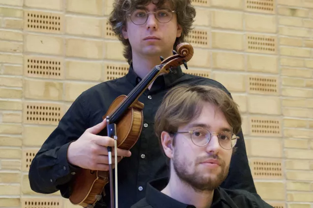 Foto. Två studenter varav en håller i en violin.