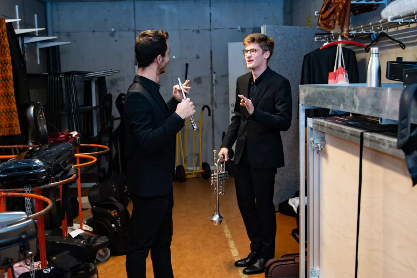 Två symfoniorkesterstudenter pratar backstage. Fotograf: Michel Thomas.